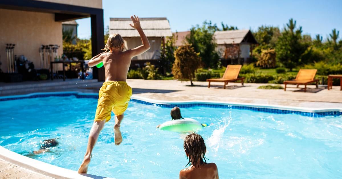 kids jumping in backyard pool